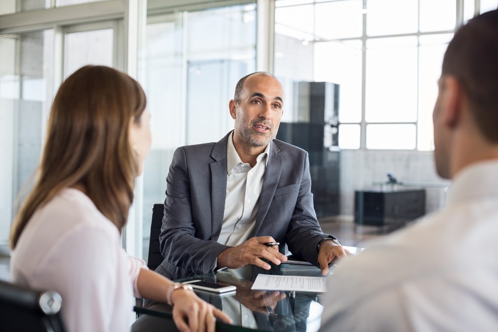 A Jones Square employee talking with two clients that both own small businesses and are looking for outsourced invoice processing services in the Plano, Texas area.